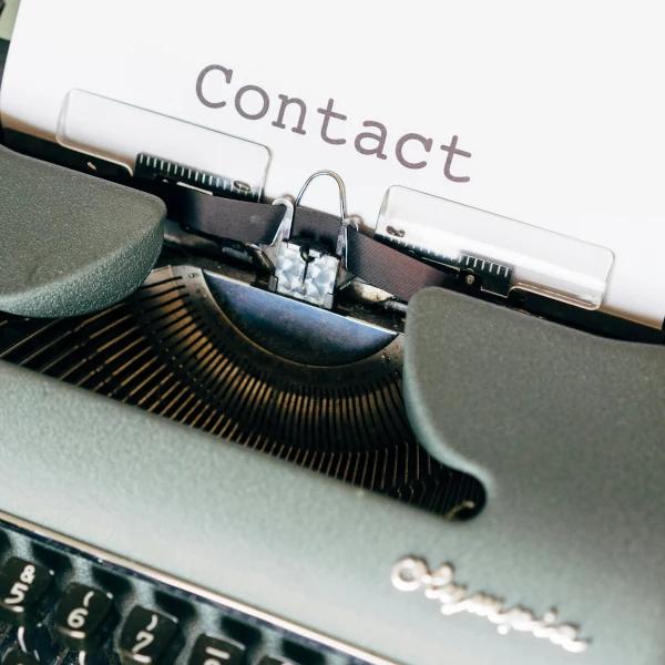 An old typewriter with a sheet of paper that says 'Contact'.